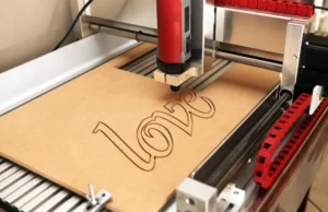 Máquina de Grabado Láser Universal Laser Systems cortando un logotipo corporativo en una caja de madera.