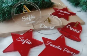 Adornos de árbol de Navidad cortados con láser en acrílico transparente y rojo, mostrando grabados personalizados.