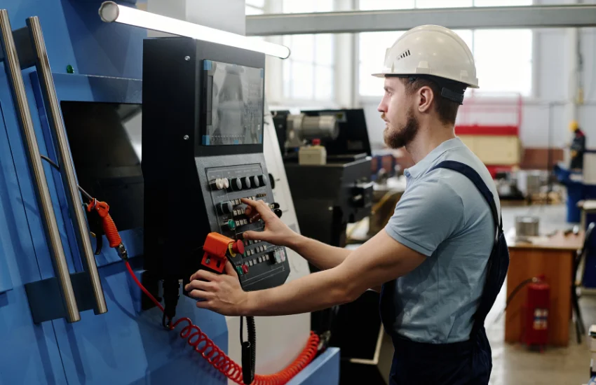 Taller industrial con un router CNC apagado y una luz roja de advertencia en el gabinete de control, representando el impacto del tiempo muerto en la producción.
